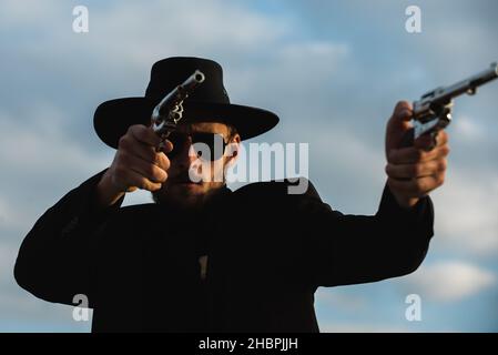 Wanted western. Cowboy with weapon. American bandit, western man with hat. West and guns. Stock Photo