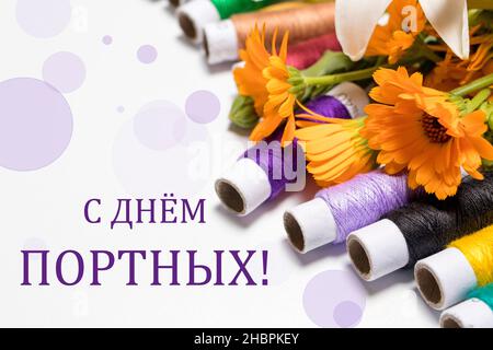 Greeting card with multi-colored threads and the text in Russian, translation from Russian: Happy Tailors Day. Stock Photo