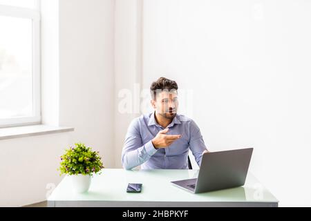 Smiling young businessman sit at desk talk on webcam having video call or conversation with client Stock Photo