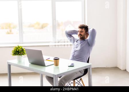 Young man smiling as he reads the screen of a laptop while relaxing Stock Photo