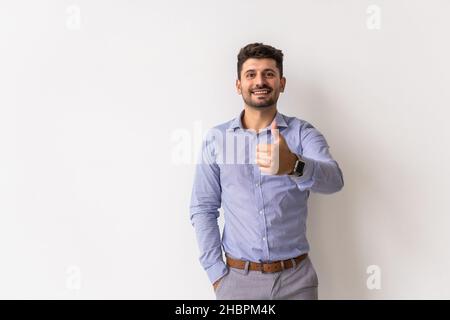 Young happy man with thumbs up sign in casuals isolated on white background. Stock Photo