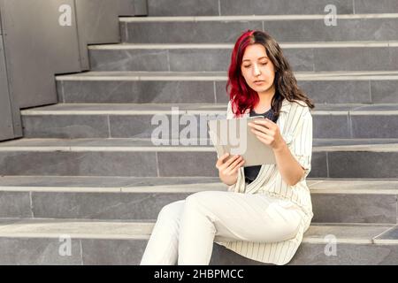 Successful Business woman Using Digital Tablet outhdoors Sitting on the Stairs near the Office Building Stock Photo