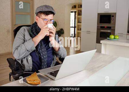 Contemporary businessman or freelancer drinking coffee in front of laptop while looking through morning news Stock Photo