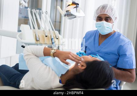 Focused hispanic dentist attentively listening to female patient toothache complains in dental office Stock Photo