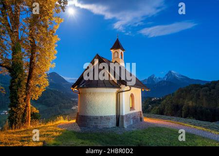 die Kirchleitn Kapelle am Mitterweinfeld hoch über Berchtesgaden mit dem maechtigen Watzmann im Hintergrund  in der blauen Stunde der hereinbrechenden Stock Photo
