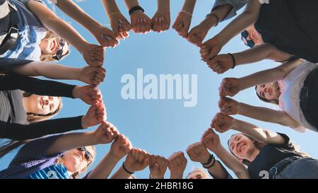 A group of girls makes a circle from their fists of their hands. Stock Photo