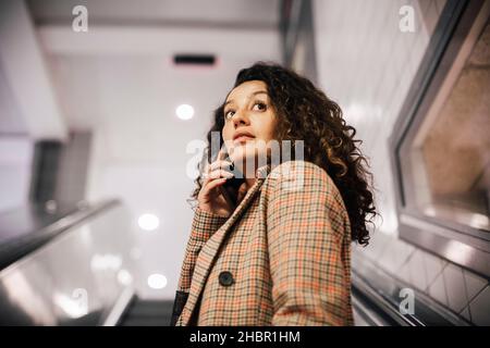 Female professional talking on smart phone at escalator Stock Photo