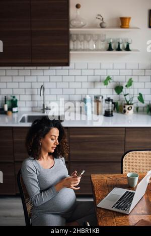 Female freelancer using smart phone while working at home Stock Photo