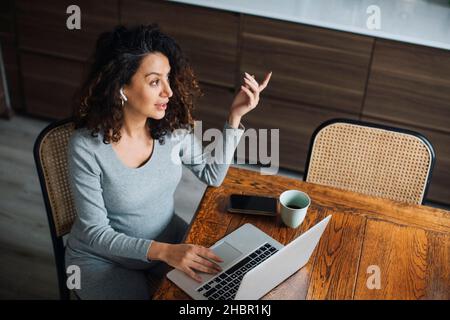 Female entrepreneur talking on bluetooth while working on laptop Stock Photo