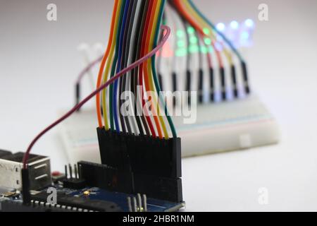 Set of jumper wires connected to a microcontroller board that completes the circuit with Breadboard and LED showing prototyping electronic projects Stock Photo