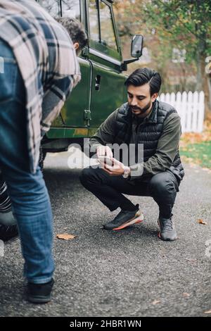Father by son using smart phone on driveway Stock Photo
