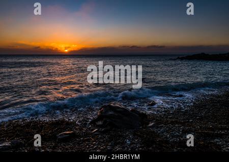 Sun setting through the clouds over Mount's Bay from Trevean Cove near Penzance, Cornwall, UK Stock Photo