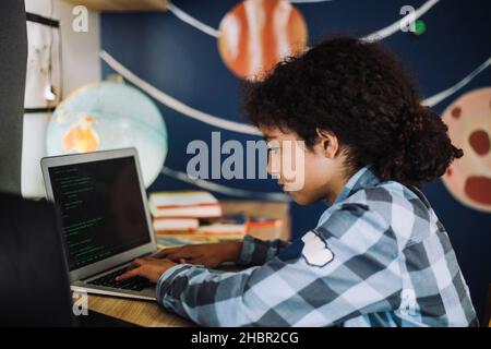 Girl concentrating while learning coding on laptop at home Stock Photo