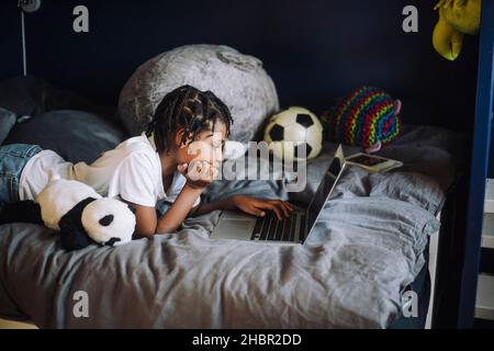 Ambitious girl learning coding on laptop in bedroom Stock Photo