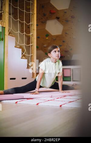 Female athlete looking away while doing stretching exercise at home Stock Photo