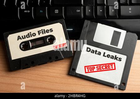 Data leak concept: audio cassette and floppy disk with top secret data on a wooden table Stock Photo