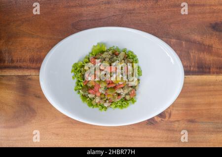 Traditional Russian Christmas and New year salad Olivier on white plate on wooden background. Top view, close up with copy space. High quality photo Stock Photo