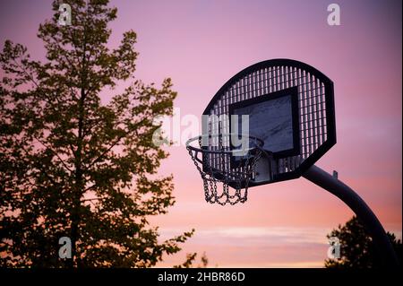 A closeup shot of a basketball hoop on a purple sunset Stock Photo