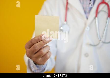 doctor hand hold a sticky note against yellow background  Stock Photo
