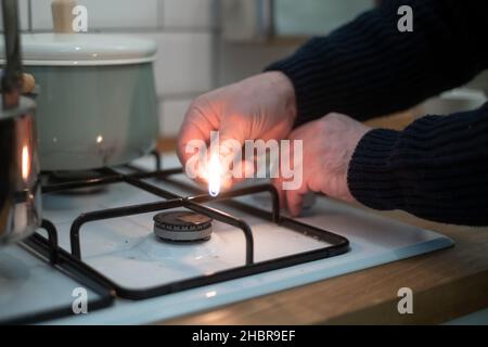 Male hand turn on gas stove using match Stock Photo