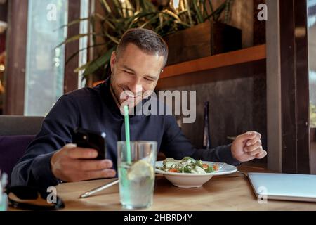 Businessman is using his phone while having lunch in restaurant Stock Photo