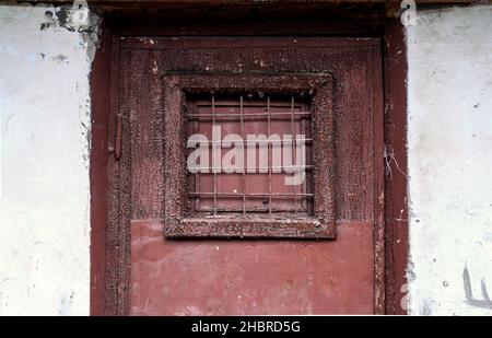 A fragment of an old rusty metal wooden door with a lattice window Stock Photo