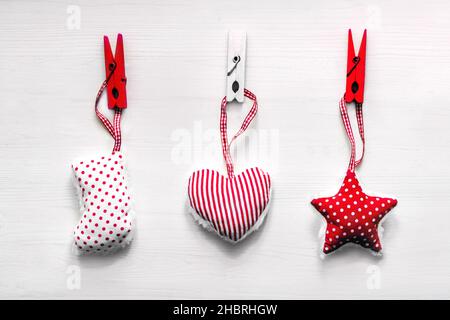 Christmas toys hanging on clothespins. Merry Christmas and New Year holiday decorative red white background. Holiday gift concept Stock Photo