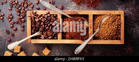 Food background with three kinds of coffee: beans, milled, instant in wooden box on old concrete brown background. Rustic stile. Selective focus. Top Stock Photo