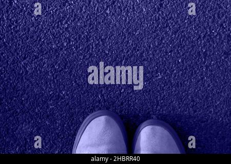 Defocus cropped part white gumshoes on asphalt background. Foot and legs seen from above. Selfie great for any use. Color of the year 2022. Very peri Stock Photo