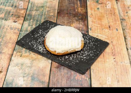 cinnamon roll with grated coconut topping on black slate plate Stock Photo