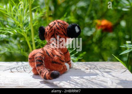 Cute funny little toy handmade woolen tiger, felting from wool, rear view Stock Photo