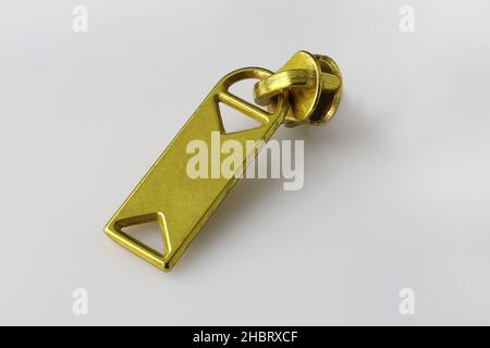 Metal zipper for clothes, bags or shoes. Fittings for making wallets of gold color. gold zipper sliders on a white background. Accessories for sewing Stock Photo