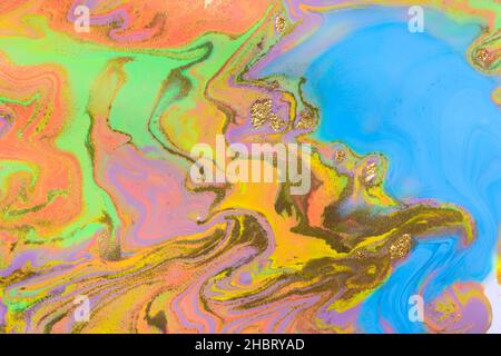 Gold powder on colorful mix liquid inks and blue copyspace Stock Photo