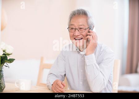 Elderly man using a smart phone to make calls at home Stock Photo