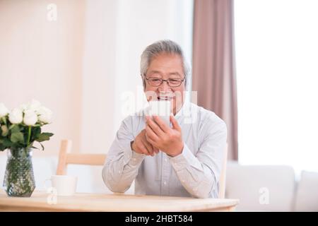 Older man using a smartphone at home Stock Photo