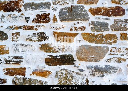 Bright wall from natural rectangular stone with white lime plaster, traditional technology, nice texture and structure. Rural. Stock Photo