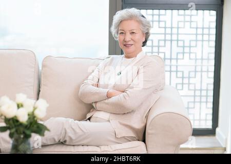 Happy old woman sitting on the sofa Stock Photo