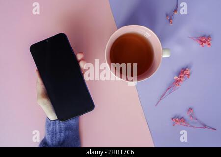 Top view 2022 goals lettering in notebook, cup of tea and flowers on pink purple background. Purple trendy colors 2022. Selective focus. Stock Photo
