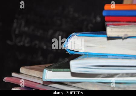 Pile of books with notes paper on wooden table with chalkboard in background.Pile of books on wooden table with blackboard background Stock Photo