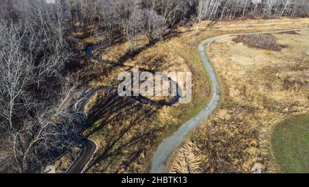 Hiking trail with stream alongside it in autumn woods Stock Photo