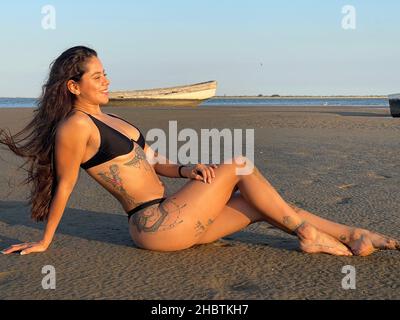 Young and beautiful woman with statuesque fitnes body in swimsuit, bikini on estuary beach between sand and mangrove swamp  mujer joven y hermosa de c Stock Photo