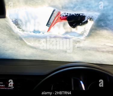 Driver clearing snow from windscreen Stock Photo