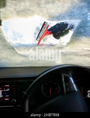 Driver clearing snow from windscreen Stock Photo