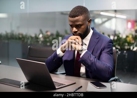 Pensive african american young entrepreneur working on laptop Stock Photo