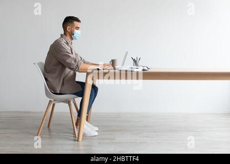 Man in disposable facemask working on pc at home office Stock Photo