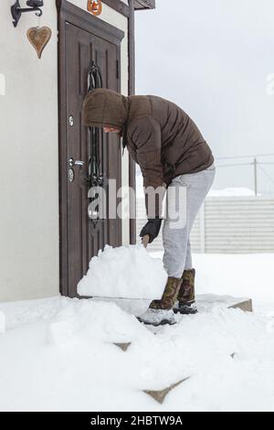 Man shoveling snow from the steps of his house Stock Photo