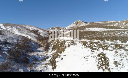 Alps - aerial view. Mountains under the snow in winter. Panorama of snow mountain range landscape with blue sky. Stock Photo