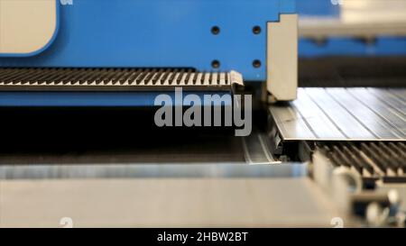 Cutting holes perforation stamping of metal sheets on industrial CNC machine. Close-up shot of a CNC coordinate punching press perforates metal sheet. Stock Photo