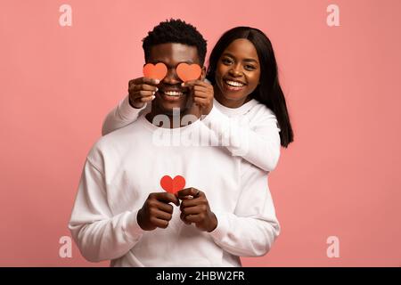 Loving black lady covering her boyfriend eyes with Valentine cards Stock Photo