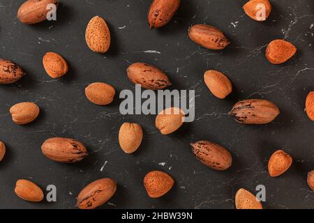 Mixed whole pecan nuts and almonds on black marble board, flat lay photo Stock Photo